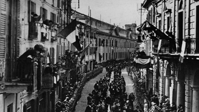 Pavia, corso Strada Nuova, Celebrazioni per l'XI Centenario del 'Capitolare Olonese di Lotario I'. Il corteo sotto l'egida del professore Plinio Fraccaro sfila verso il Castello visconteo, a sinistra sul balcone, Lina e Camillo Golgi, 21 maggio 1925 (CHL A_42_19_001)