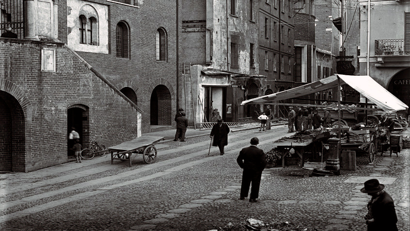 Pavia, piazza Grande (oggi della Vittoria), Palazzo del Broletto e imbocco di via del Campanile ora via Omodeo, Torre Civica e bancarelle del mercato, 1928. (CHL M_76_2_28)